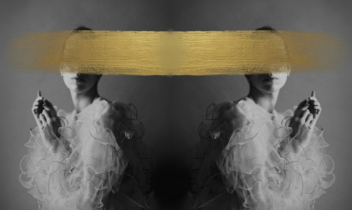 Composizione fotografica simmetrica in bianco e nero di due figure speculari di profilo, che indossano abiti eleganti e vaporosi con volant. Una spessa ed evidente pennellata di vernice dorata copre orizzontalmente gli occhi di entrambe le figure, creando un forte contrasto con lo sfondo grigio neutro