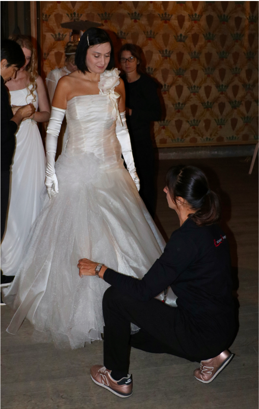 Simona Maria Giantin, piegata nell'atto di sistemare un abito da sposa ad una modella